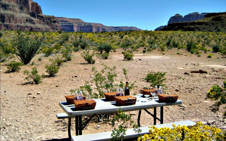 Grand Canyon picnic setup with baskets and drinks on a table during helicopter tour landing.