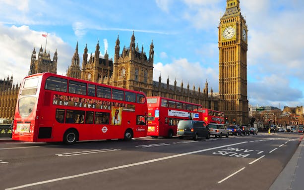 Red double-decker buses near Big Ben and the Houses of Parliament in London.