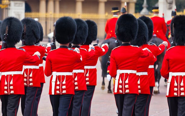 Guards in red uniforms at Buckingham Palace, London, during a ceremonial event.