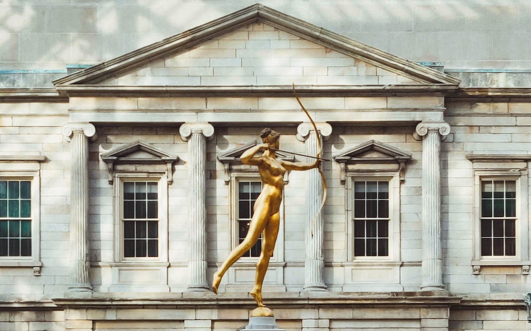 Golden statue of Diana in front of the Met Museum facade, New York City.