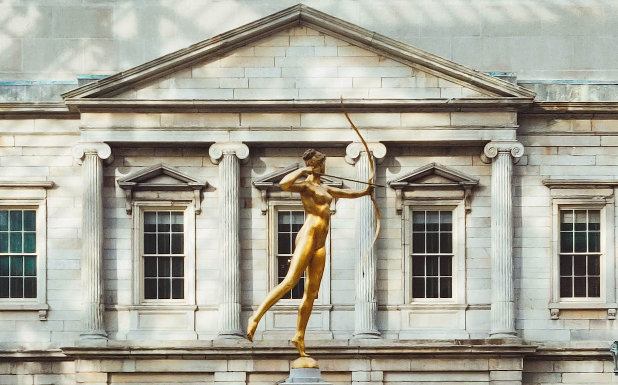 Golden statue of Diana in front of the Met Museum facade, New York City.