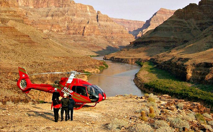 Helicopter on Grand Canyon West Rim with tourists overlooking the Colorado River.