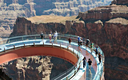 Visitors walking on the Grand Canyon Skywalk with canyon views below.