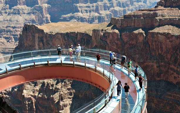 Visitors walking on the Grand Canyon Skywalk with canyon views below.