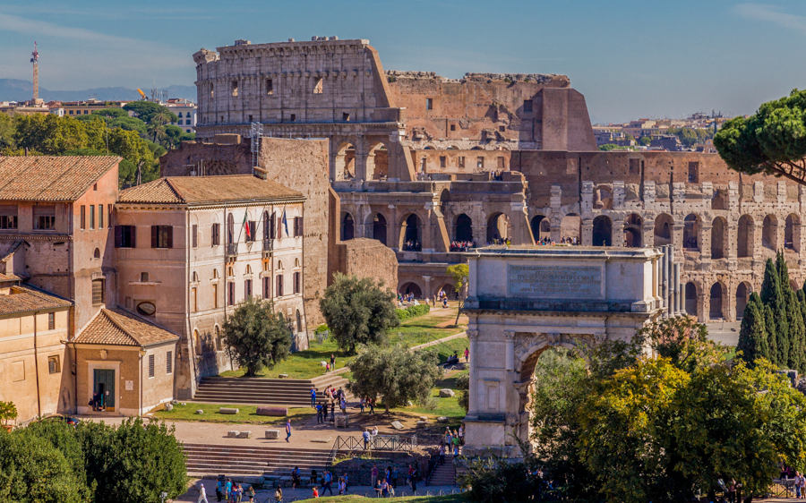 Colosseum in Rome with nearby ancient structures and greenery.
