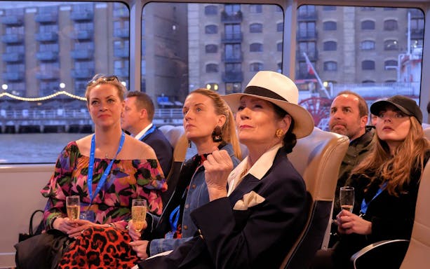 Passengers enjoying a Thames cruise with views of London buildings.
