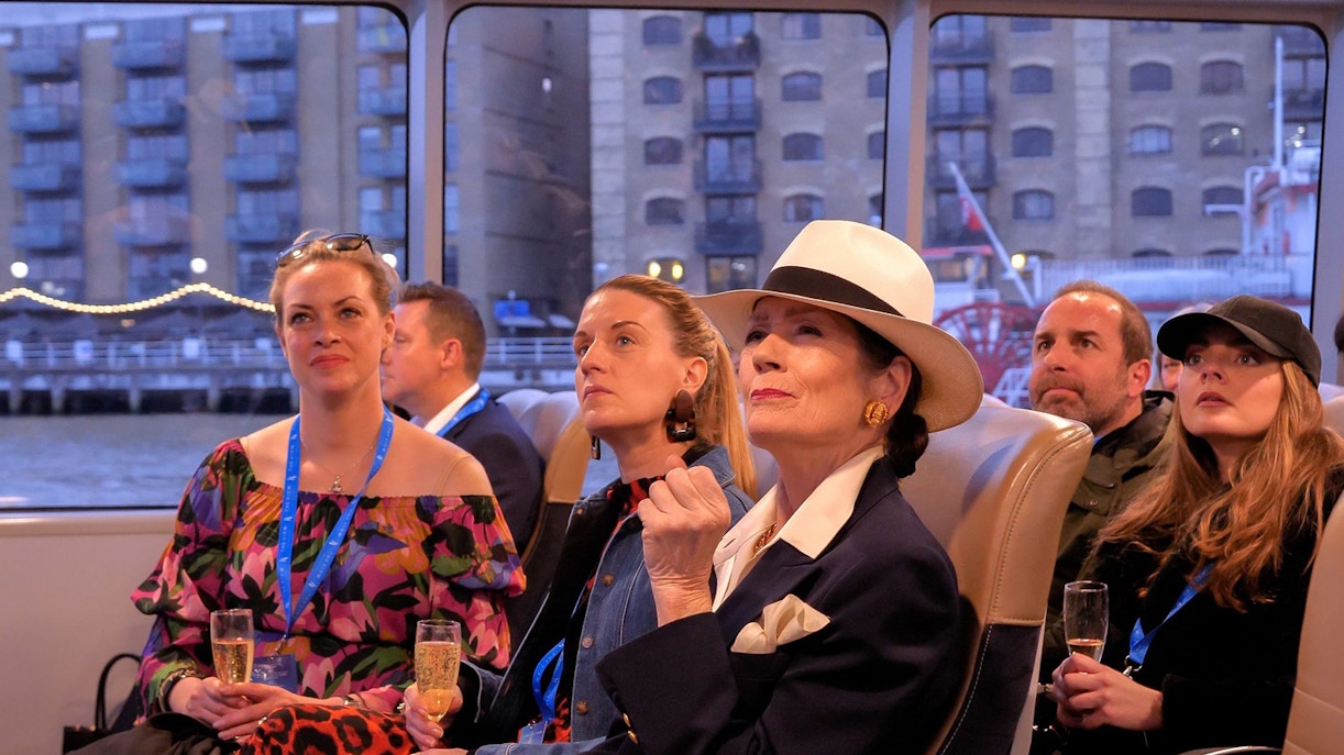 Passengers enjoying a Thames cruise with views of London buildings.