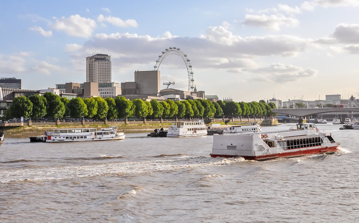 Thames River cruise boat with London Eye in the background.