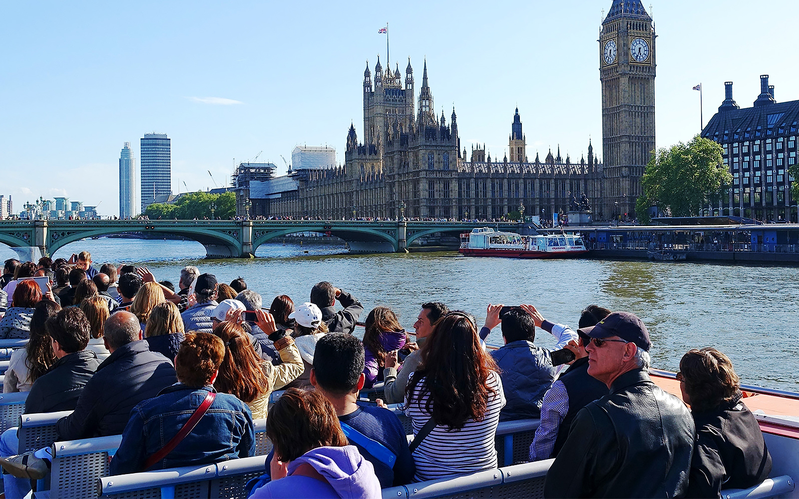 Tourists on a Thames cruise viewing the Houses of Parliament and Big Ben in London.