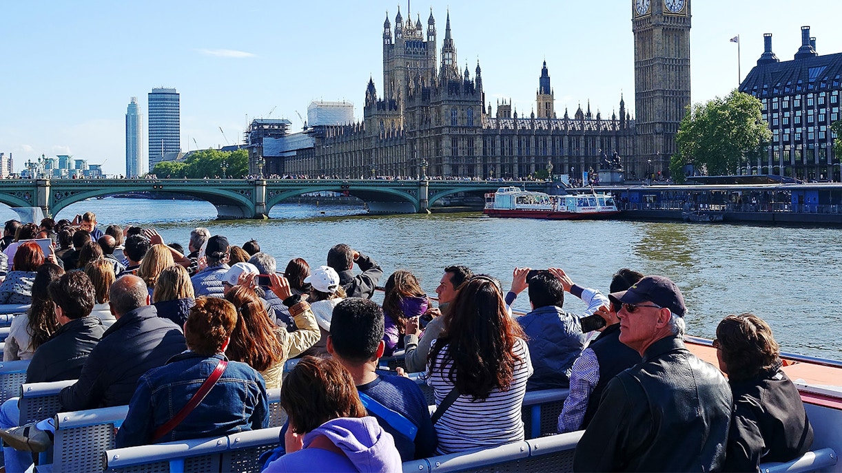 Tourists on a Thames cruise viewing the Houses of Parliament and Big Ben in London.