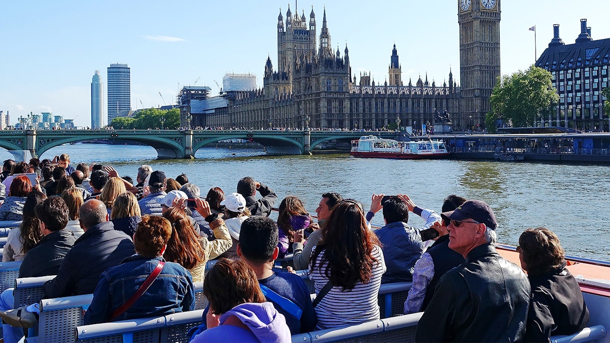 Tourists on a Thames cruise viewing the Houses of Parliament and Big Ben in London.