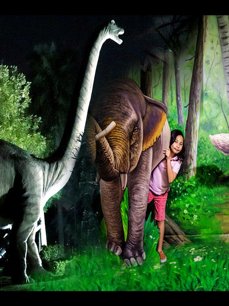 Children interacting with dinosaur and animal sculptures at Magic Park, part of the Combo: Warner Bros + Garden Glow tour.