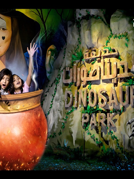 Visitors at Magic Park Dubai in a cauldron with Dinosaur Park sign.