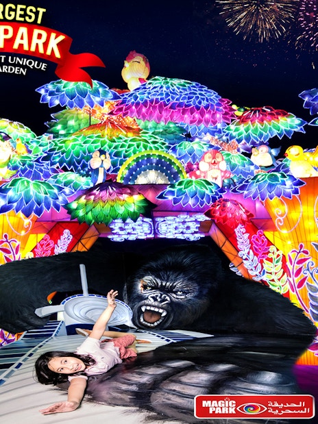 Glow Garden entrance with colorful illuminated sculptures and a child posing on a 3D gorilla artwork.