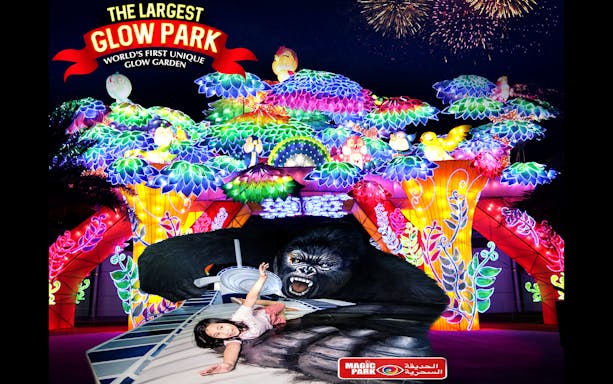 Glow Garden entrance with colorful illuminated sculptures and a child posing on a 3D gorilla artwork.