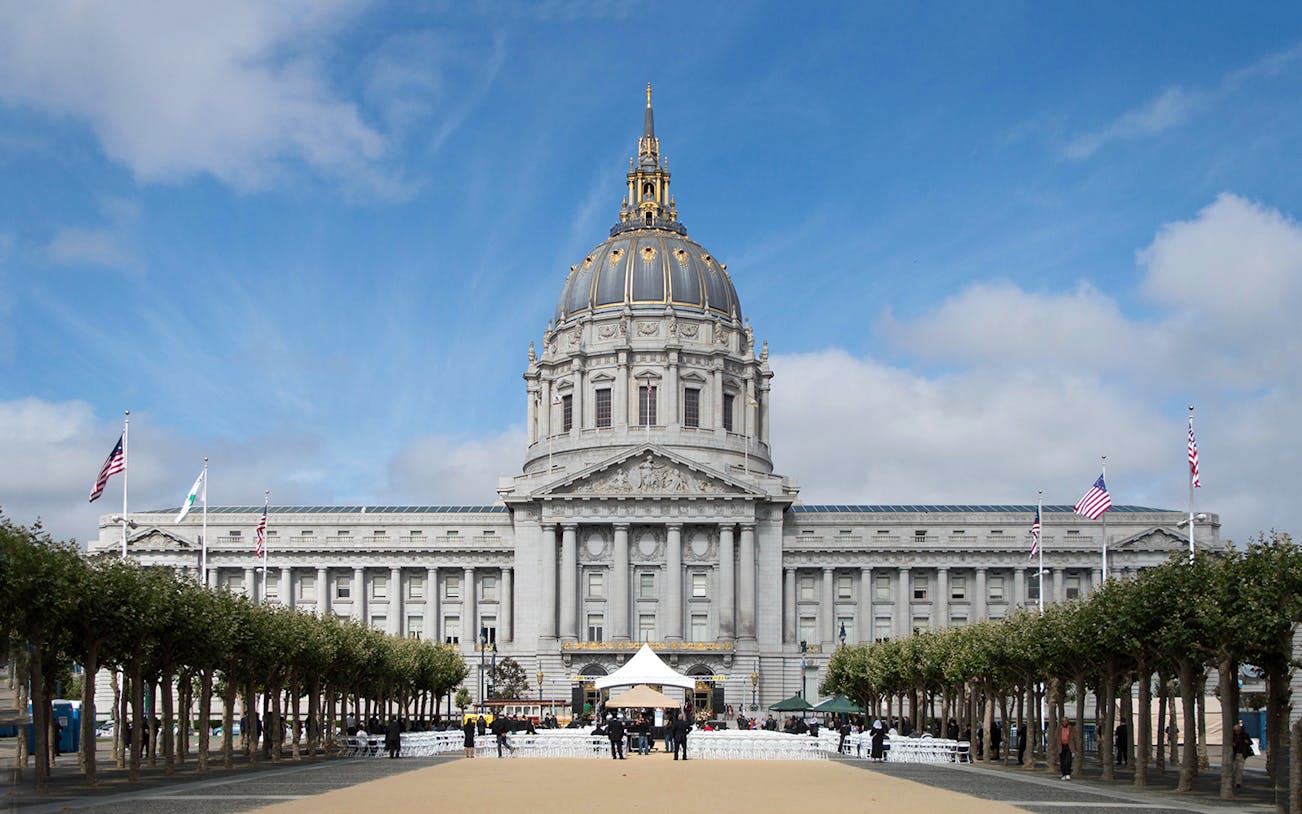 San Francisco City Hall with flags and trees lining the path.