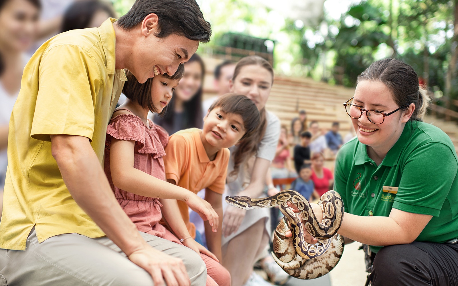 Family interacting with a snake at Singapore Zoo show.