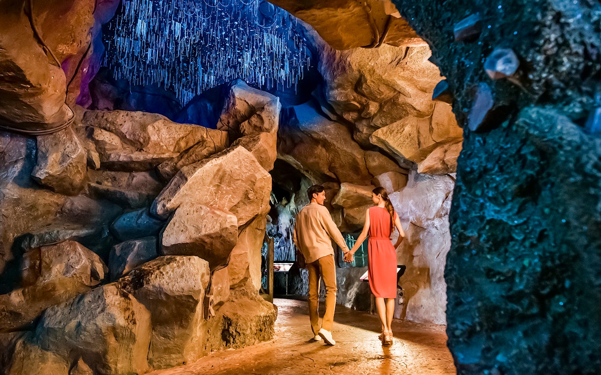 Couple walking through illuminated cave at Singapore Night Safari.