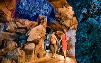 Couple walking through illuminated cave at Singapore Night Safari.