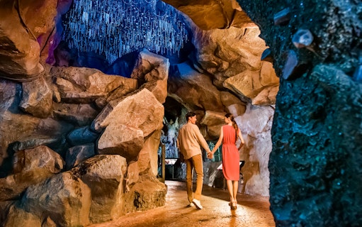 Couple walking through illuminated cave at Singapore Night Safari.