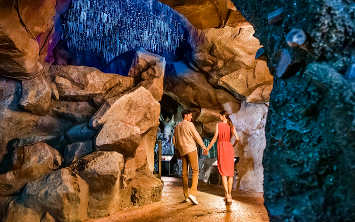 Couple walking through illuminated cave at Singapore Night Safari.