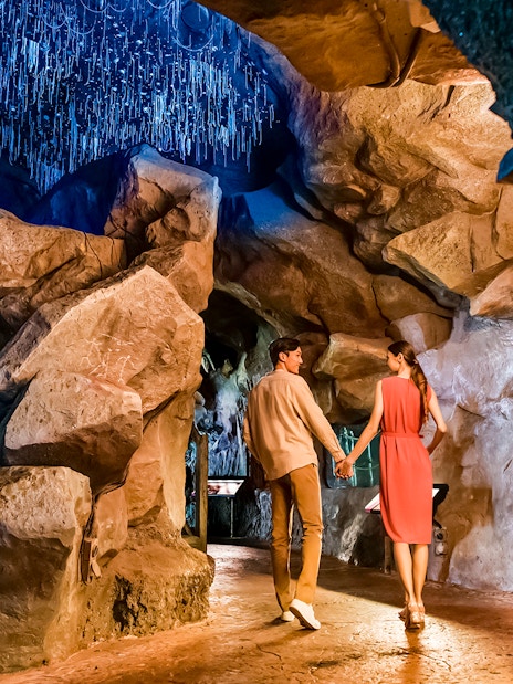 Couple walking through illuminated cave at Singapore Night Safari.