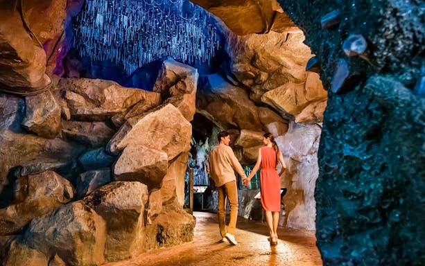 Couple walking through illuminated cave at Singapore Night Safari.