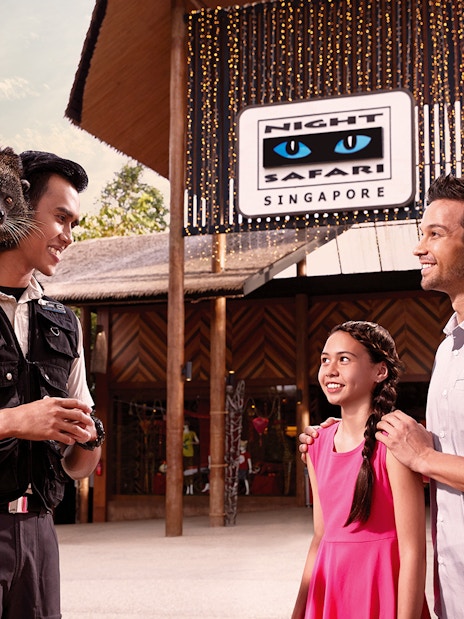 Guide with binturong on shoulder at Night Safari entrance, Singapore, interacting with visitors.