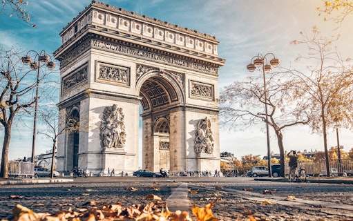 Arc de Triomphe in Paris with autumn leaves on the ground.