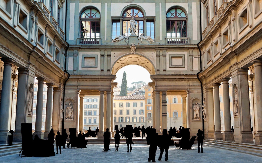 Uffizi Gallery courtyard in Florence with tourists walking through.