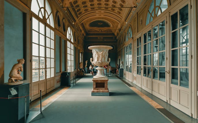 Uffizi Gallery interior with classical sculptures and large decorative urn, Florence.