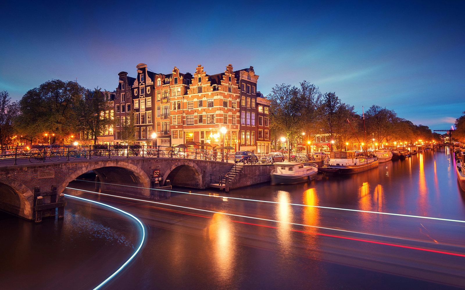 Evening canal cruise in Amsterdam with illuminated bridges and historic buildings.