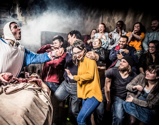 Visitors react to a theatrical performance at Amsterdam Dungeon during a sightseeing bus tour.