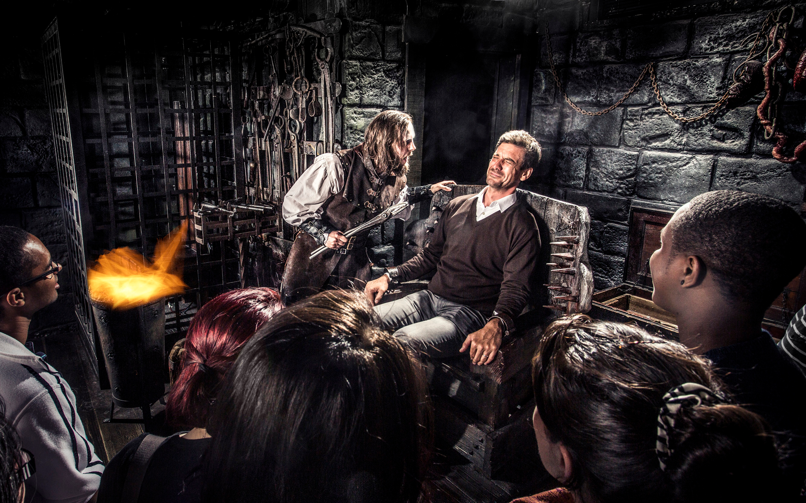 Man in medieval torture scene at Amsterdam Dungeon with onlookers.