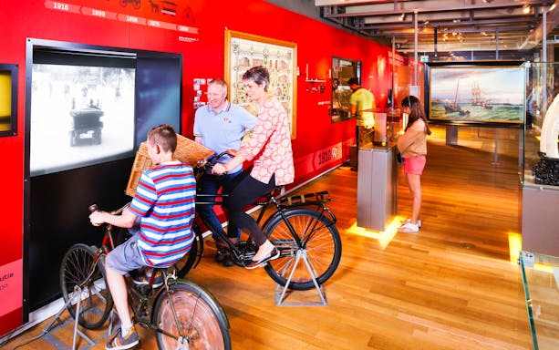 Visitors engaging with interactive bicycle exhibit at Amsterdam Museum.