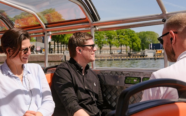 People enjoying a semi-open boat cruise in Amsterdam canal.