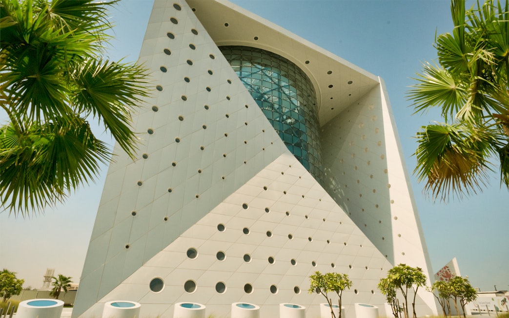 Futuristic building exterior of Green Planet in Dubai with palm trees.
