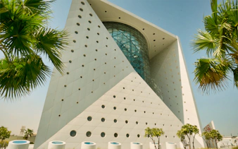 Futuristic building exterior of Green Planet in Dubai with palm trees.