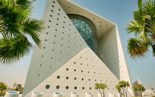 Futuristic building exterior of Green Planet in Dubai with palm trees.