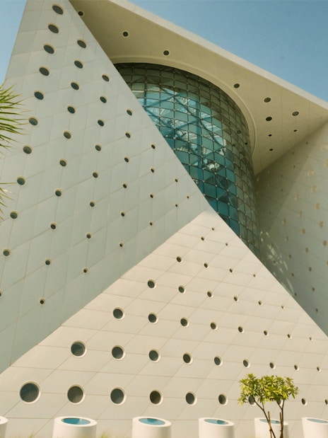 Futuristic building exterior of Green Planet in Dubai with palm trees.