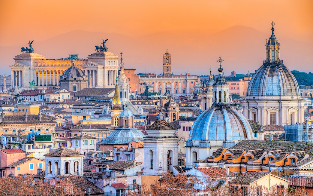 Rome skyline with domes and the Altar of the Fatherland at sunset.