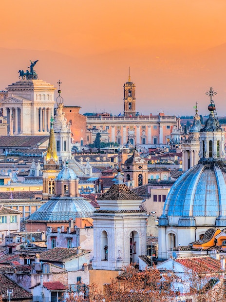 Rome skyline with domes and the Altar of the Fatherland at sunset.