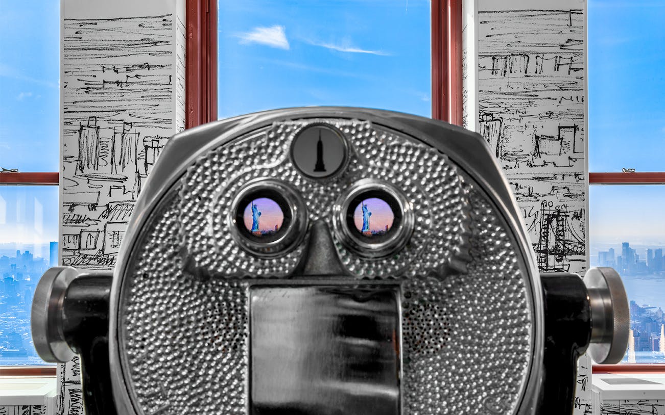 Coin-operated binoculars at Empire State Building Observatory with skyline view.