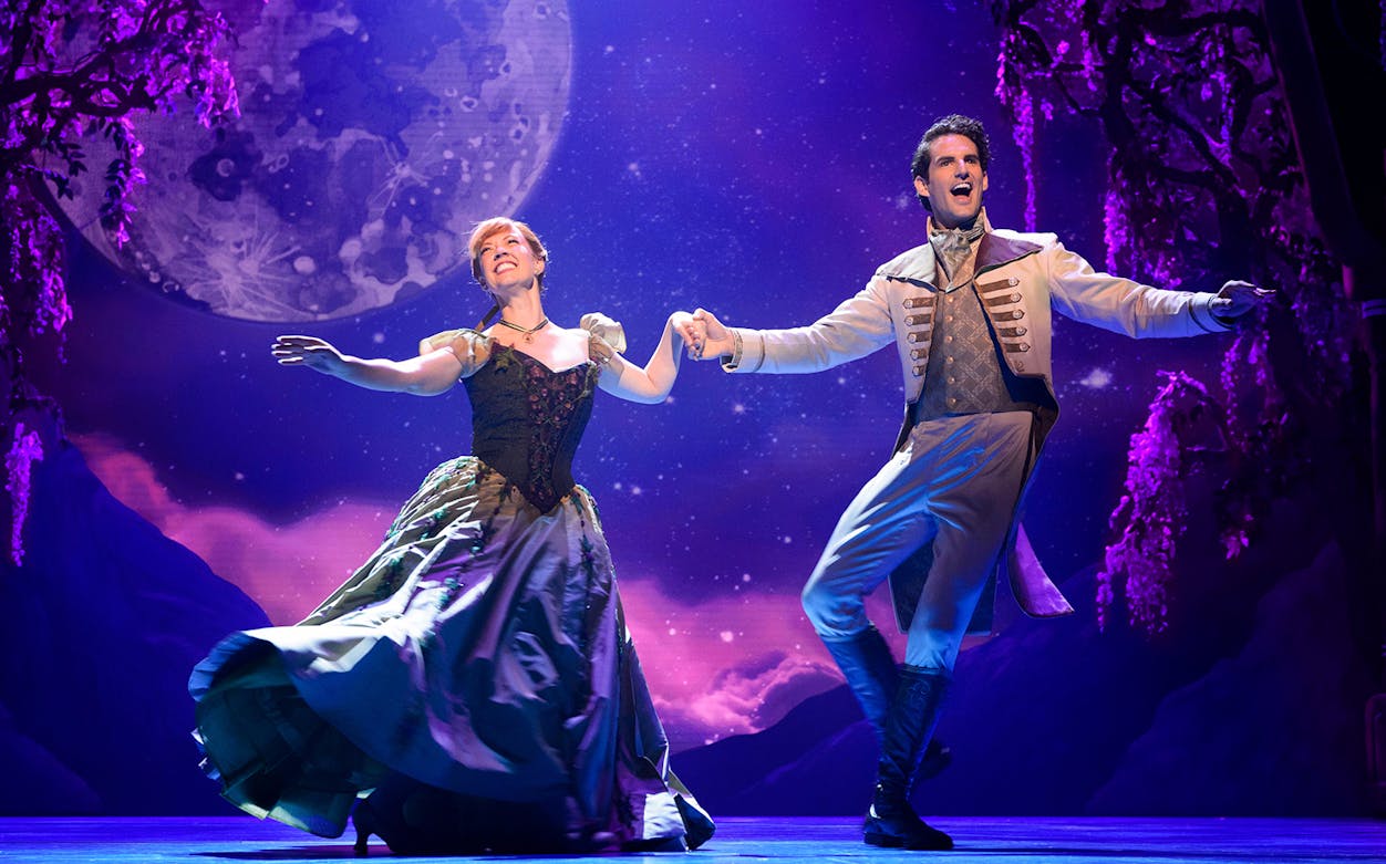 Performers dancing on stage in a scene from the Frozen musical.