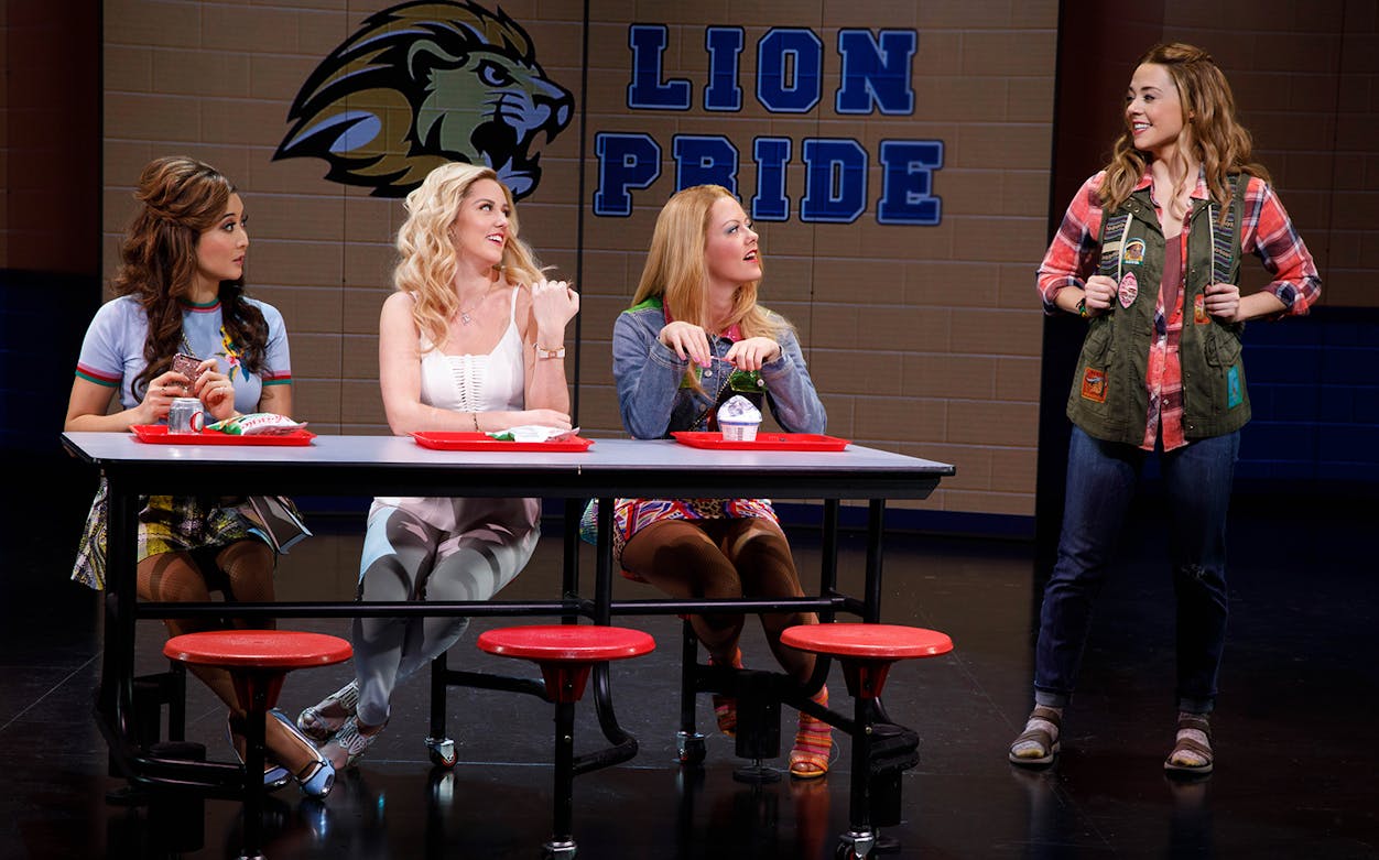 High school students at a cafeteria table in a scene from Mean Girls musical.