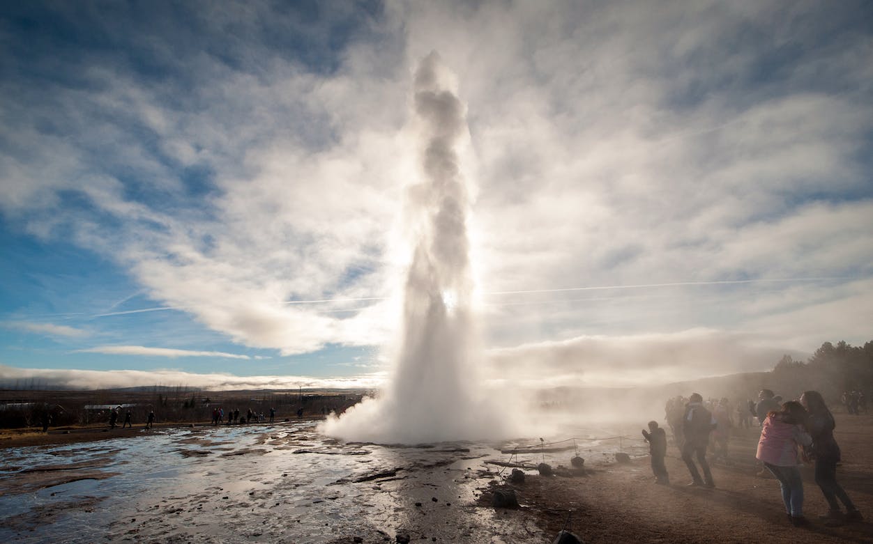 Geyser eruption in Iceland's Golden Circle with tourists observing.