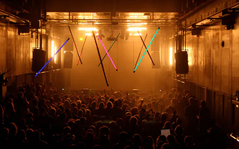 Crowd enjoying a vibrant nightclub in Amsterdam with colorful lights.