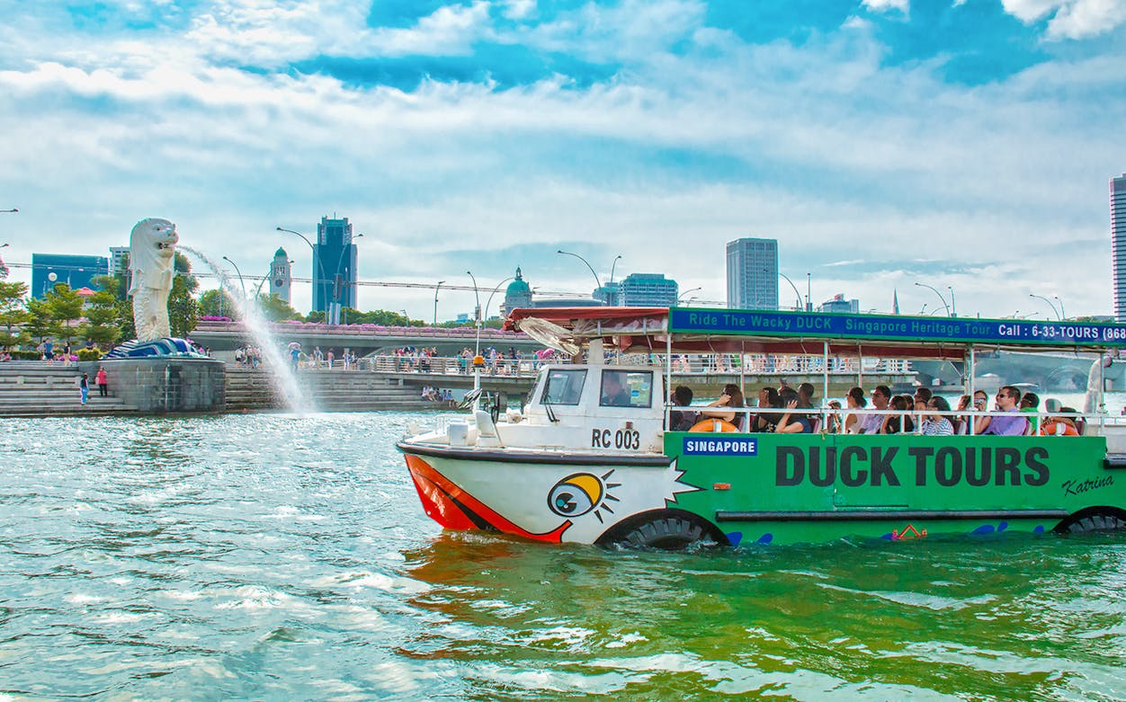 Duck tour boat on Singapore River near Merlion statue, part of FunVee Singapore bus tour.