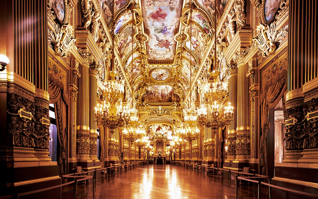 Opera Garnier's grand hall with ornate chandeliers and detailed ceiling frescoes, Paris.