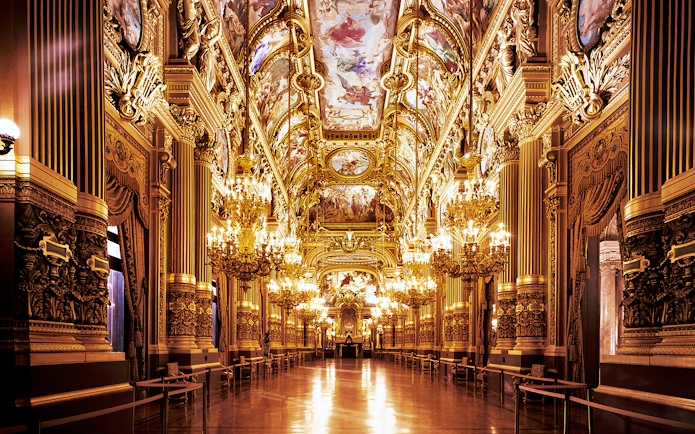 Opera Garnier's grand hall with ornate chandeliers and detailed ceiling frescoes, Paris.